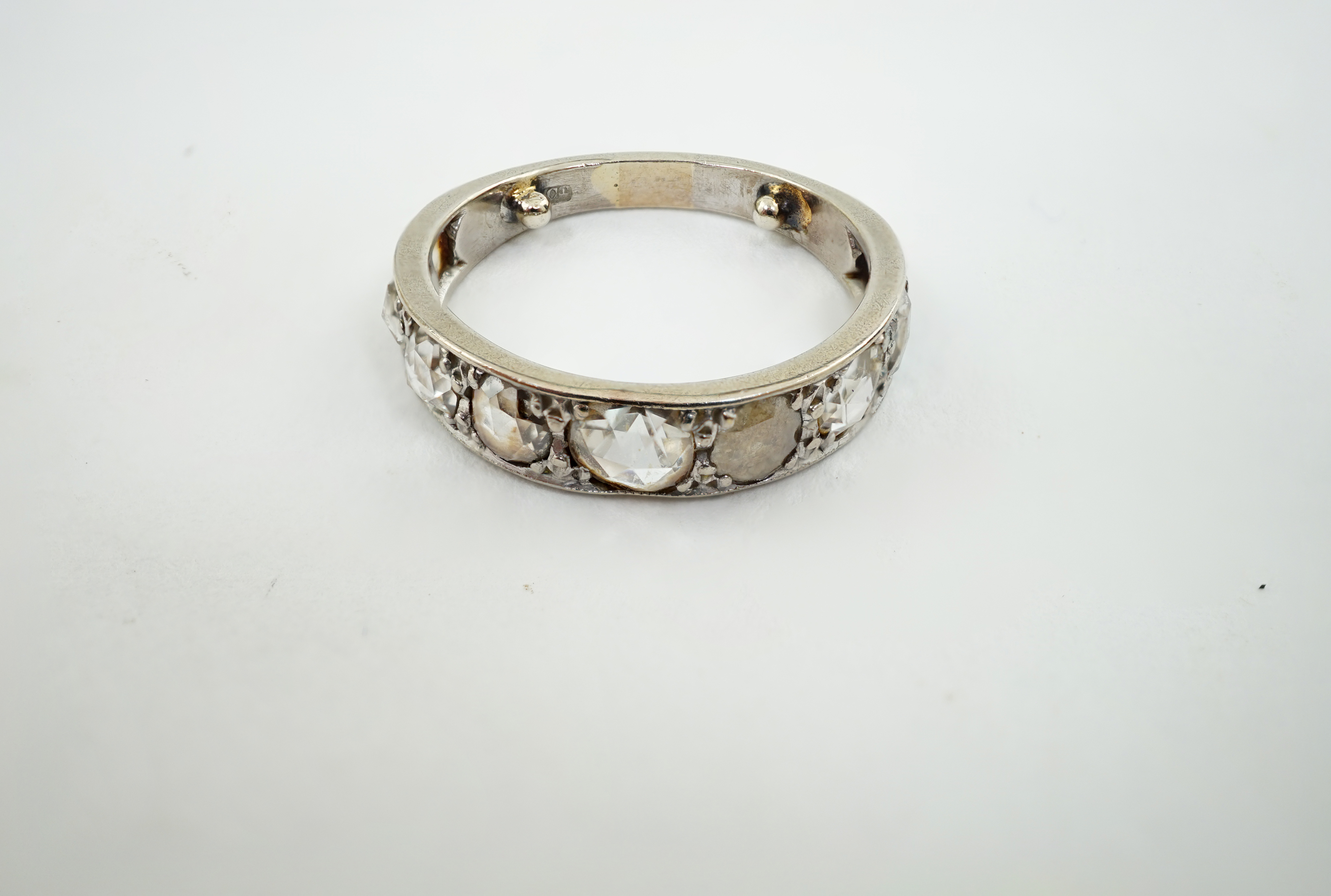 A white gold and nine stone graduated rose cut diamond set half hoop ring